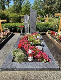 Stehender Stein hergestellt aus Granit umrandet von einer gleichfarbigen Granit Einfassung und eingravierter Blume im Stein  | © Messerschmidt GmbH