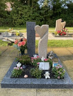 Stehender Urnengrabstein bestehend aus zwei Stelen eine mit herausgearbeitetem Herz aus zwei verschiedenen Granitarten mit Einfassung. | © Messerschmidt GmbH