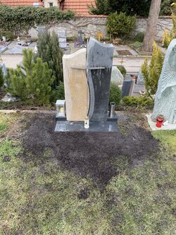 Ein stehender Rasengrabstein, gefertigt aus Granit und Sandstein, welcher mit einem Kreuz verziert ist | © Messerschmidt