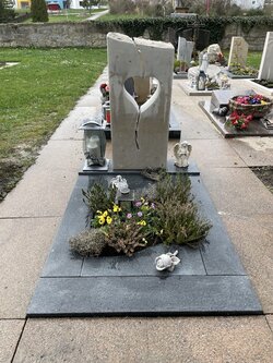 Stehender Grabstein hergestellt aus Sandstein mit mittig liegendem Herz und umrandet von einer Granit Einfassung | © Messerschmidt GmbH