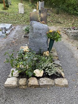 Auf dieser Grabstelle steht ein stehender Grabstein aus Granit mit gestückelter Einfassung. | © Messerschmidt GmbH