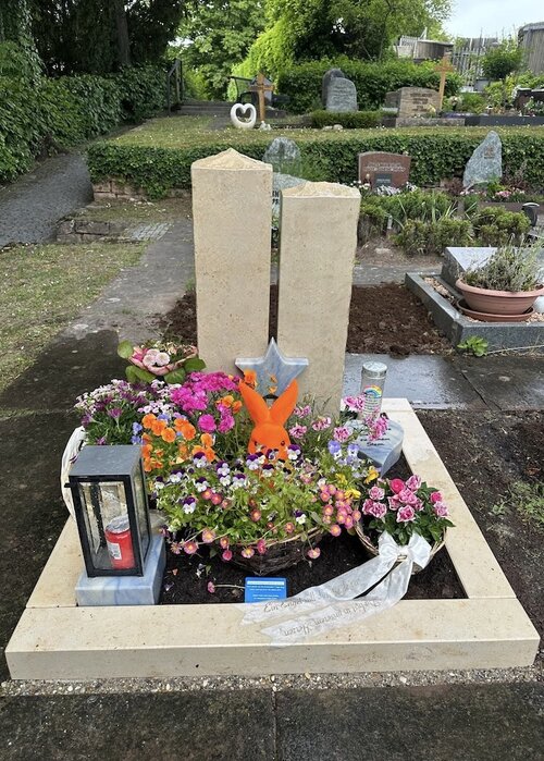 Urnengrabstein aus Jura Kalkstein mit Zwei Stelen. Einfassung ebenfalls aus Jura Kalkstein. Deko Elemente aus bläulichem Granit Azul do Macaubas. | © Messerschmidt GmbH
